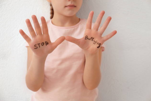 parents can support their children when faced with a bully; child with hands up reading "stop bullying"